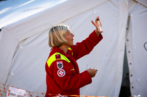 Eine Frau in Uniform zeigt ein Probenröhrchen in die Höhe.